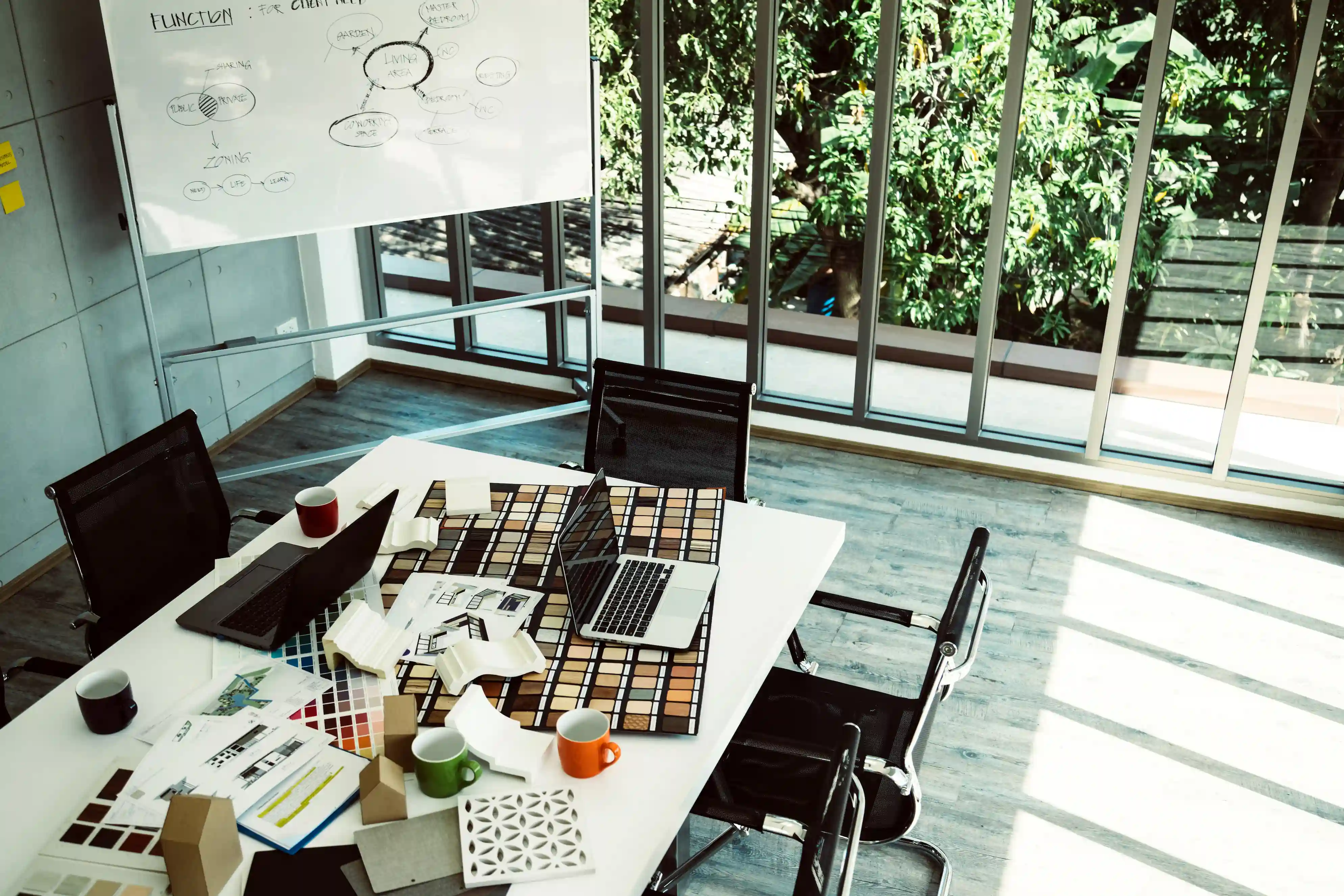 Bürotisch mit Proben und Plänen neben Whiteboard